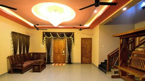 A spacious living area with a wooden sofa, a wooden bench, a staircase, and a chandelier. - SPR Paradise Resort (Vanur)