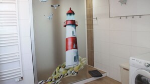 A bathroom with a mural of a lighthouse, a washing machine, and a towel rack. - Ostersander vacation apartment - centrally located between Ihlow, Timmel, Aurich and bathing lakes (Ihlow)