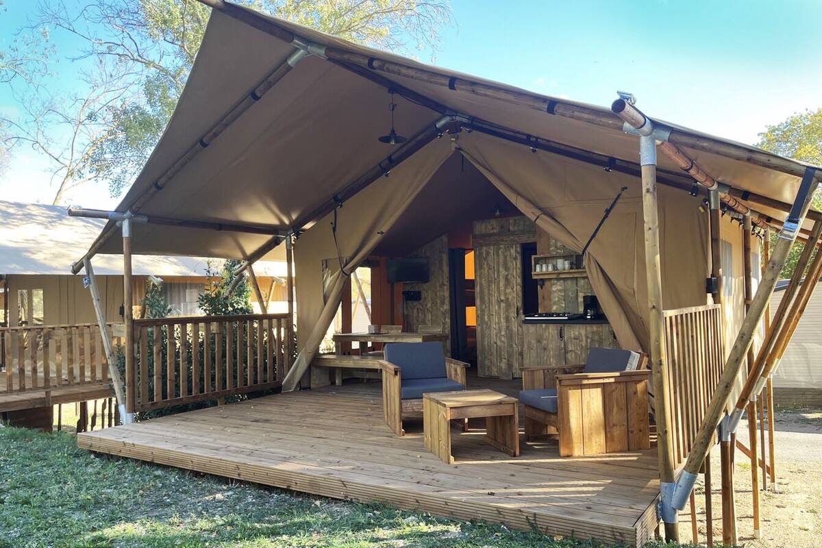 Een overdekt buitengebied met een houten terras, zitplaatsen en een televisie.