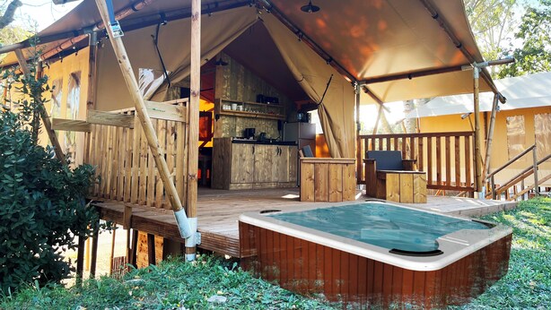 Una carpa de madera rústica con jacuzzi y zona de cocina.