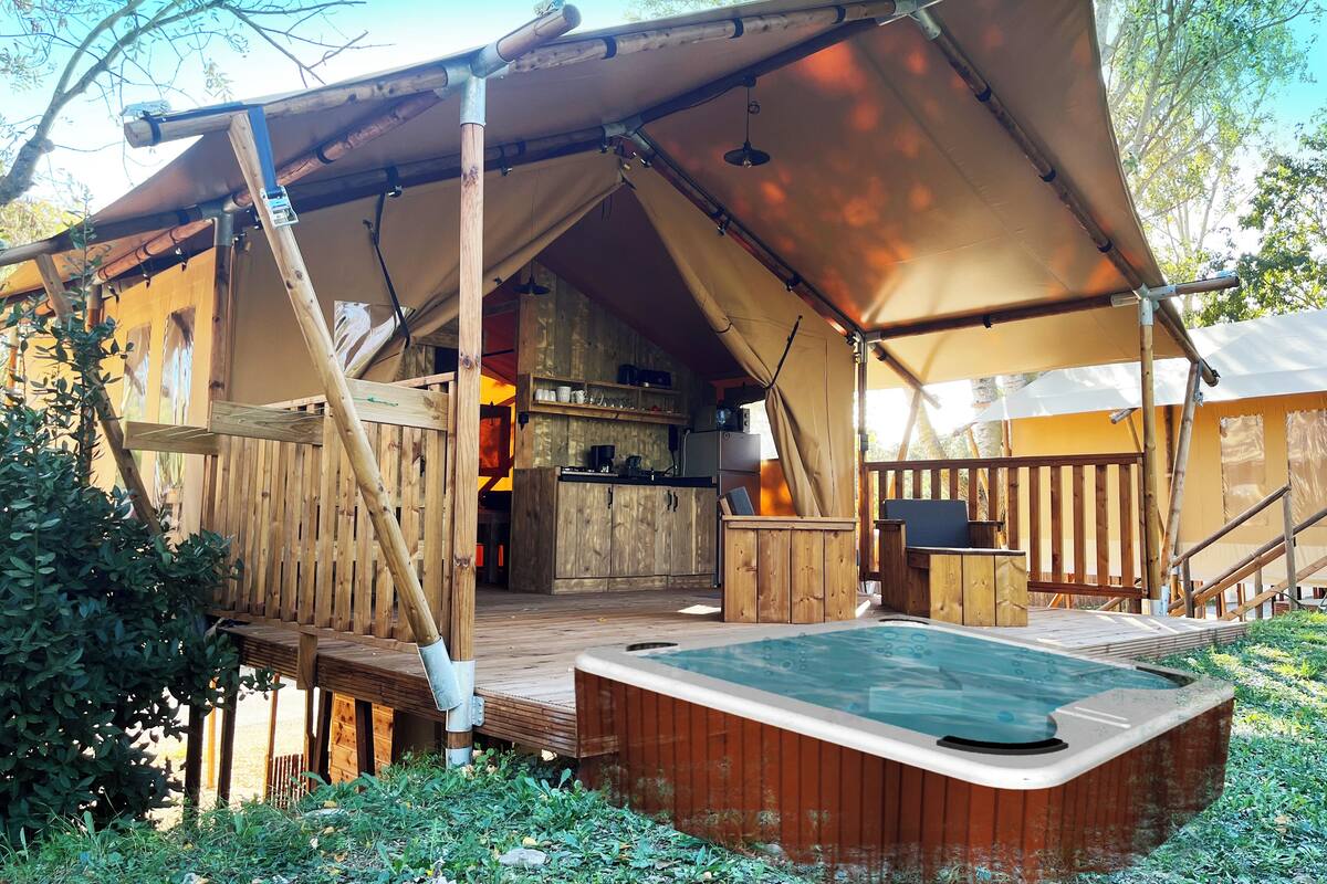Een rustieke houten tent met een bubbelbad en een kitchenette.