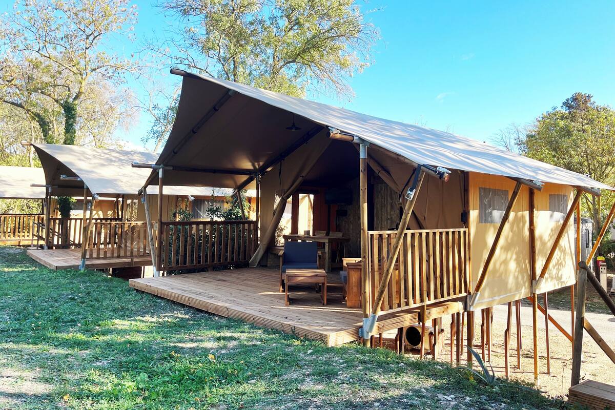 Een camping met houten huisjes, elk met een overdekte veranda en een klein terras.