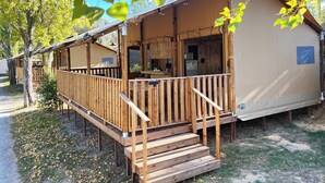 Una cabaña de madera con un porche, una zona de cocina y un pequeño espacio de estar al aire libre.