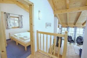 Una habitación con estructura de madera, una cama, un ventanal con cortinas y vistas al exterior.