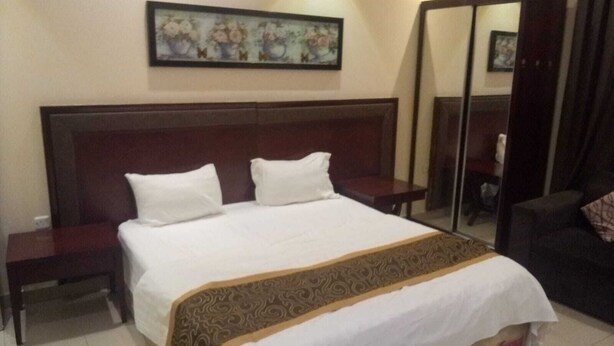 Una habitación de hotel con una cama grande, una mesita de noche, un espejo y un cuadro en la pared.