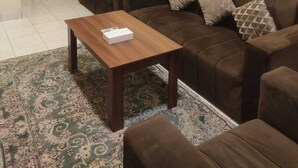 Una sala de estar con un sofá marrón, una mesa de centro de madera y un tapete estampado.