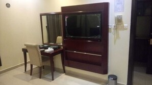 Habitación de hotel con escritorio, silla, televisor y cesto de basura.