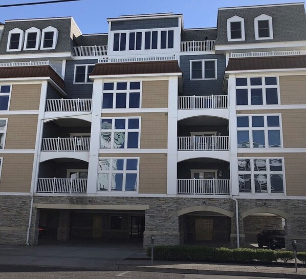 Un edificio residencial de varios pisos con balcones, acceso a garaje y fachada de piedra.