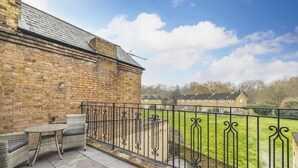 A balcony with wicker furniture, a brick wall, and a view of a house.