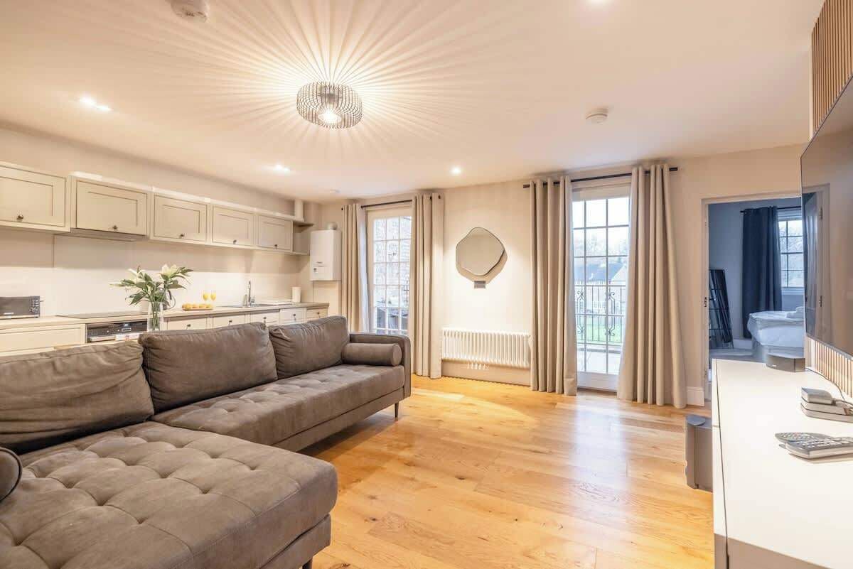 A modern living room with a sofa, a dining area with cabinets, and a kitchen with a radiator.