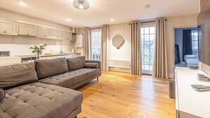 A modern living room with a sofa, a dining area with cabinets, and a kitchen with a radiator.