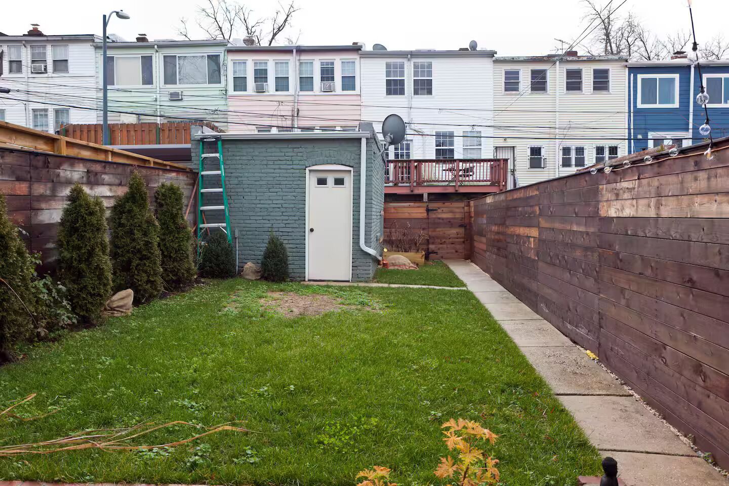 A residential backyard with a small shed, a wooden fence, and a lawn.