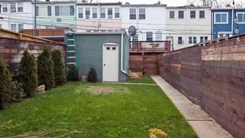 A residential backyard with a small shed, a wooden fence, and a lawn.