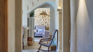 Un pasillo que conduce a una sala de estar con una pared de piedra, un sofá y un sillón mecedor.