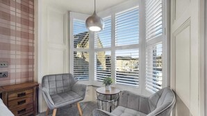 Una habitación con dos sillones grises, una mesita redonda con una planta y una lámpara colgante.