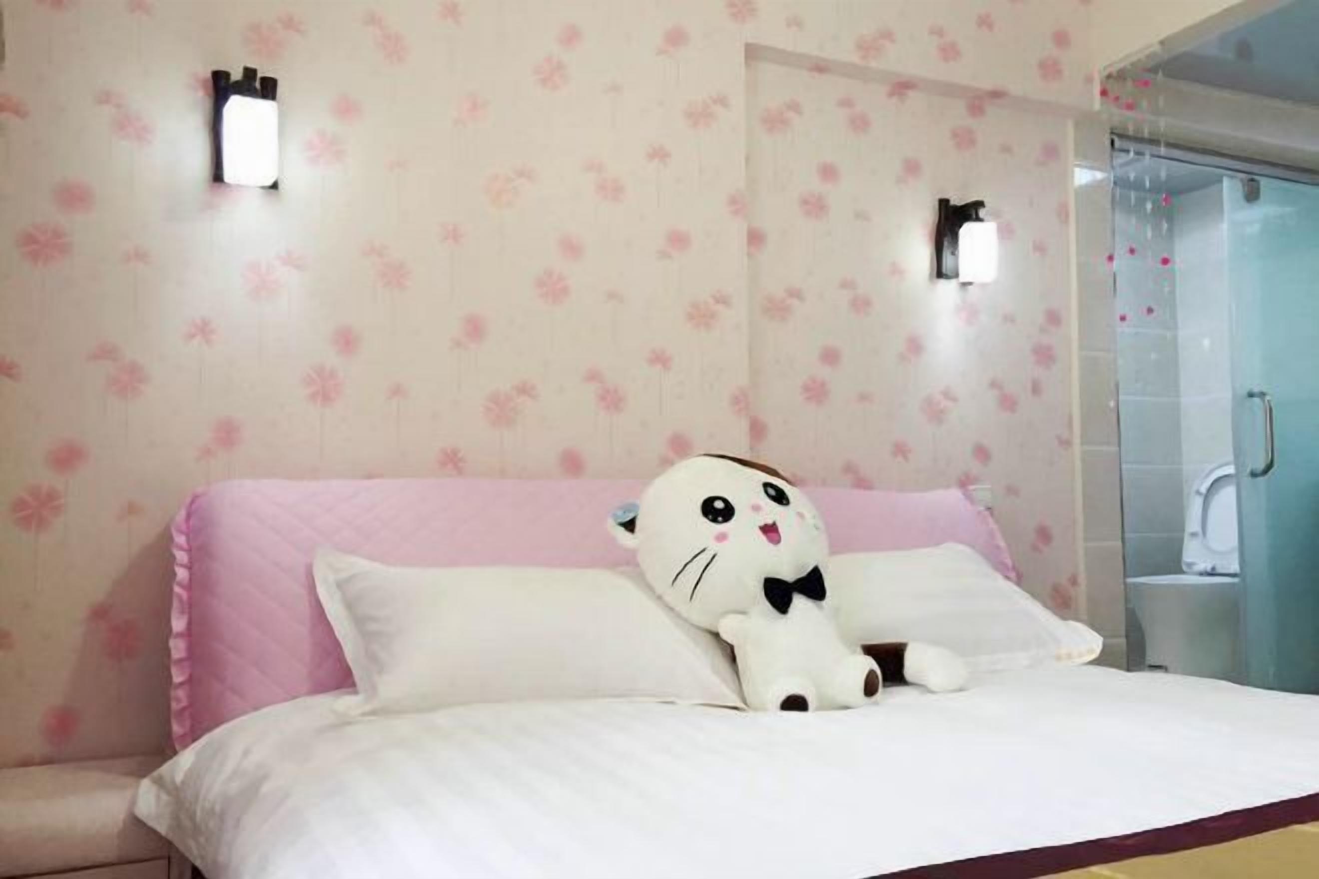 A bedroom with a bed, a plush cat toy, and a shower area.