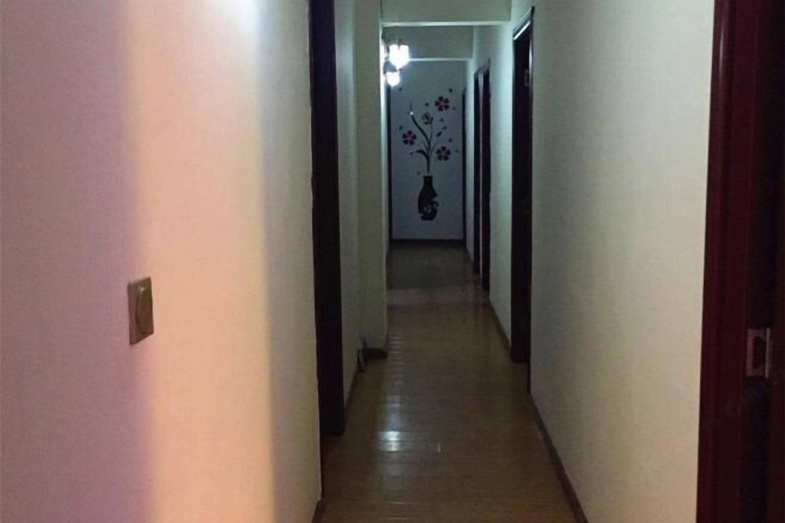 A narrow hallway with a wooden floor and white walls.