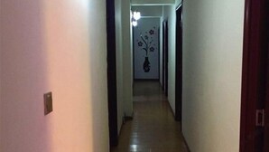 A narrow hallway with a wooden floor and white walls.