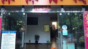 A hotel entrance with a red sign above the door, a blue police sign on the left, and a small potted plant inside.