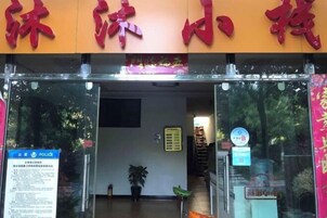 Entrada de hotel con un letrero rojo sobre la puerta, un letrero de policía azul a la izquierda y una pequeña planta en maceta en el interior.