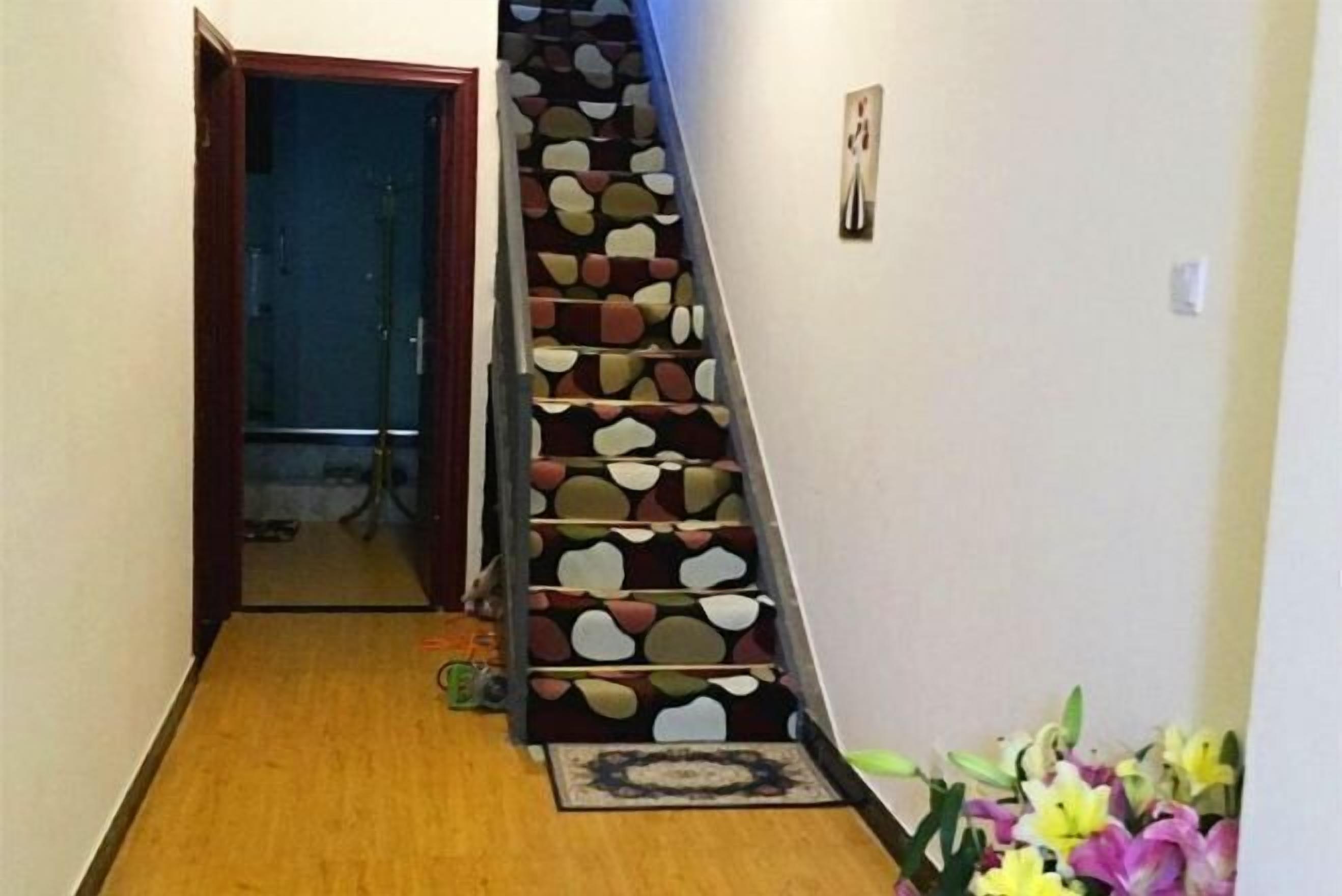 Una escalera con un diseño particular, piso de madera y una puerta que da a otra habitación.
