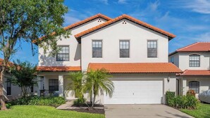 A two-story house with a red-tiled roof, a white exterior, and a garage. - Poolside Paradise on Sandy Point - with Games Room (Clermont)