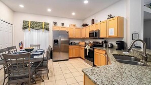 A modern kitchen with wooden cabinets, stainless steel appliances, and a granite countertop. - Caribbean Breeze Villa - Private Pool & Spa (Clermont)