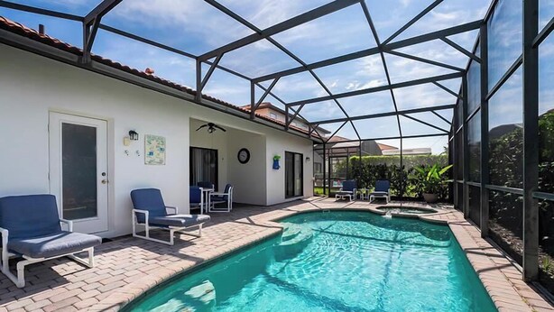 A swimming pool with a glass enclosure, lounge chairs, and a tiled patio area. - Caribbean Breeze Villa - Private Pool & Spa (Clermont)