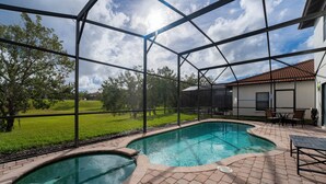 Piscina com um terraço ao redor, área de estar coberta e vista para o exterior.