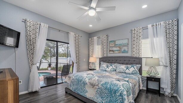 A bedroom with a large bed, a ceiling fan, a TV, and a view of the outdoors. - The Summerlight Villa - Games Room, Private Pool & Spa (Clermont)