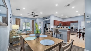 A modern kitchen with stainless steel appliances, a dining area with a wooden table and chairs, and a ceiling fan. - The Summerlight Villa - Games Room, Private Pool & Spa (Clermont)