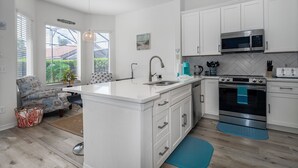 Een moderne keuken met witte kasten, een centraal eiland, roestvrijstalen apparatuur en uitzicht op de omgeving.