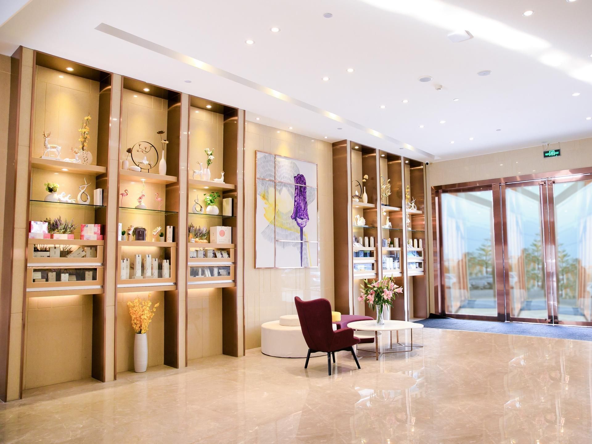 A modern hotel lobby with a reception desk, seating area, and decorative shelves.