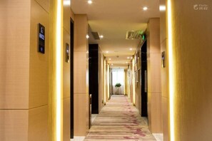 A hotel corridor with a carpeted floor, wall-mounted signs, and a ceiling with recessed lighting. - Lavande Hotel (Shenzhen)