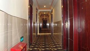 A hotel hallway with a patterned carpet, mirrored walls, and a red door at the end. - Lavande Hotel (Shenzhen)