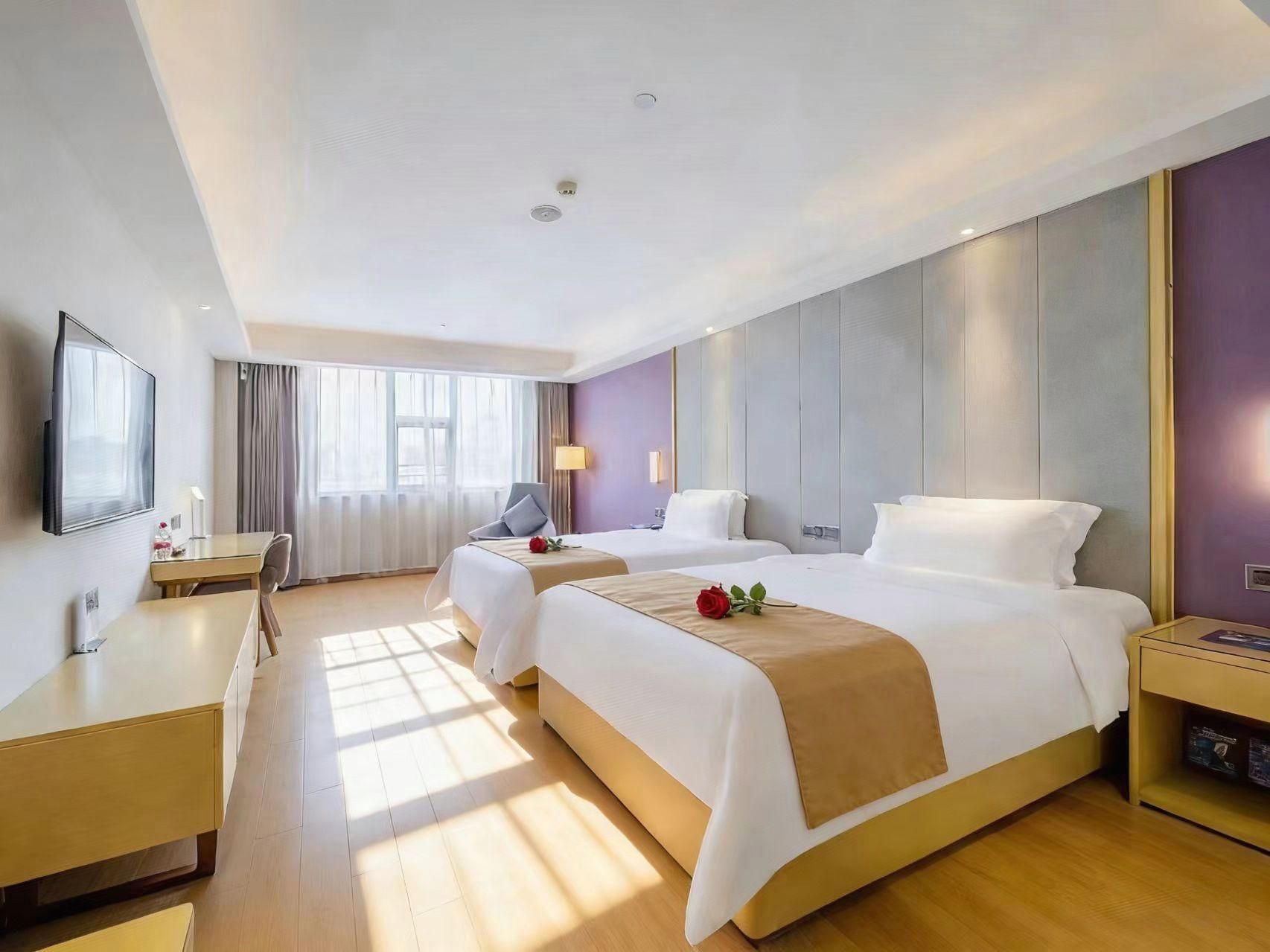 Une chambre d’hôtel avec deux lits, un bureau, une télévision et une fenêtre avec des rideaux.