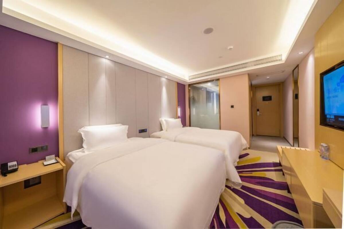 A hotel room with two beds, a TV, a desk, and a bathroom door.