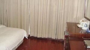 A hotel room with a bed, a wooden dresser, and a curtain. - Lavande Hotel (Shenzhen)
