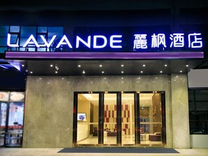 A hotel entrance with a neon sign, glass doors, and a modern interior visible through the doors. - Lavande Hotel (Shenzhen)