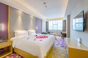 A hotel room with a large bed, a desk, a chair, a TV, and a window. - Lavande Hotel (Shenzhen)
