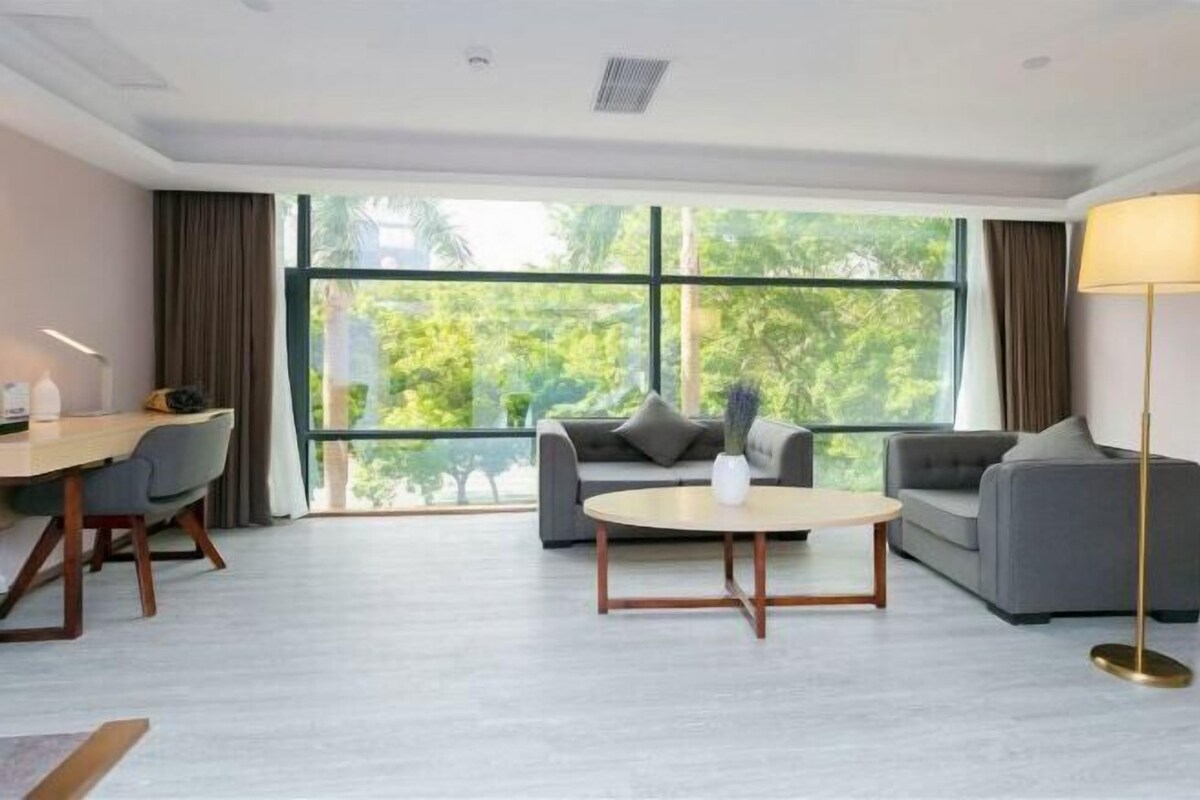 A modern living room with a sofa, a coffee table, a desk, and a lamp.