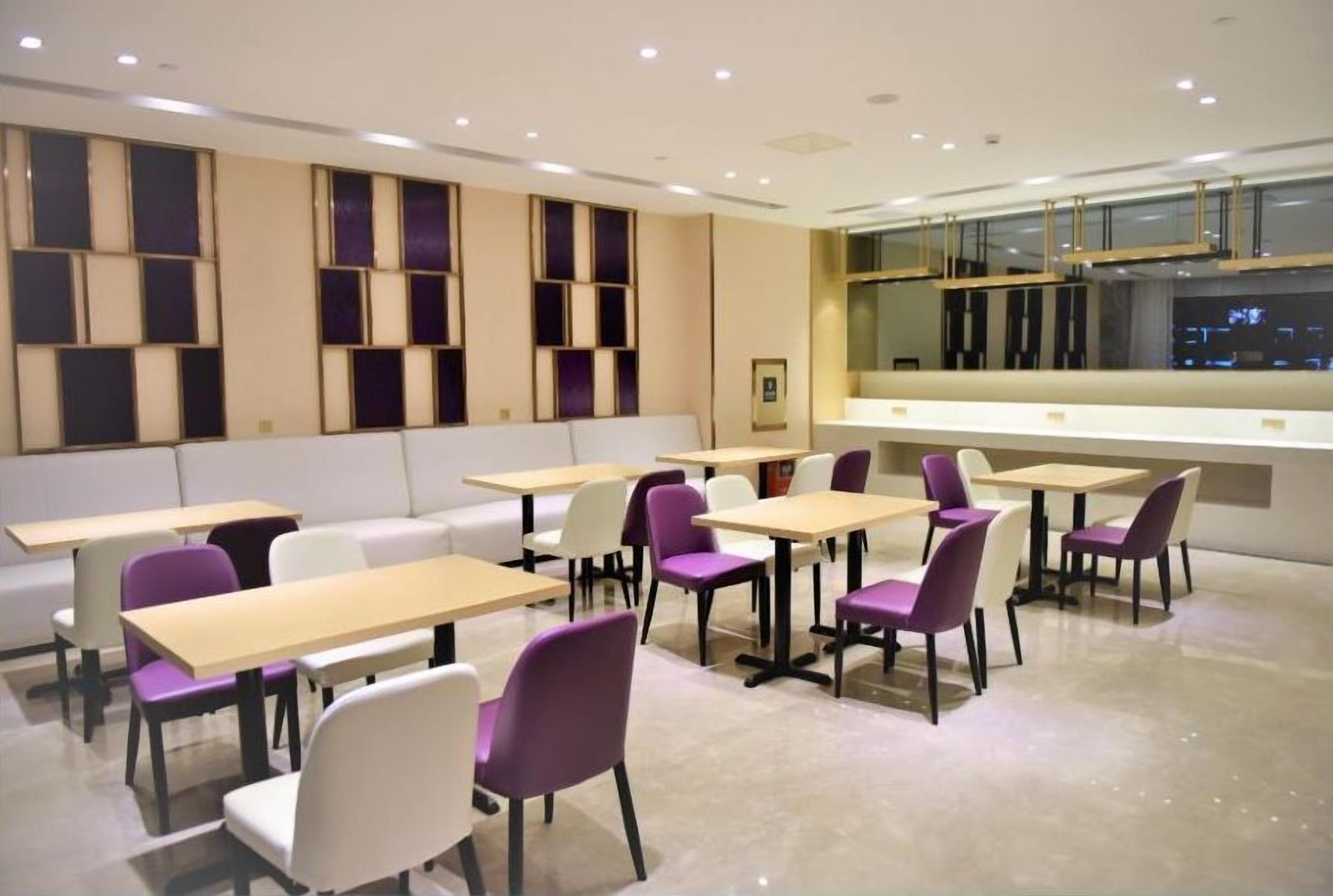 Un comedor moderno con mesas y sillas, un sofá y vistas a través de una ventana.