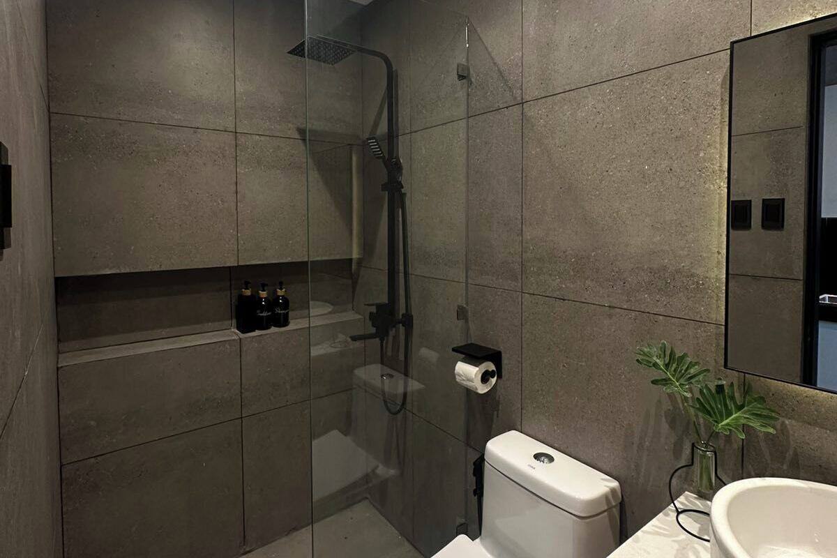 A modern bathroom with a glass-enclosed shower, a toilet, a sink, and a mirror.