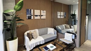 Una sala moderna con un sofá, una mesa de centro y una planta grande en maceta.
