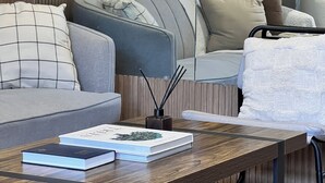 A modern living room with a sofa, a coffee table with books, and a plant.