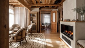 A cozy room with a fireplace, wooden ceiling, and a comfortable seating area with a rug and chairs. - VILLA VENA (Zakopane)
