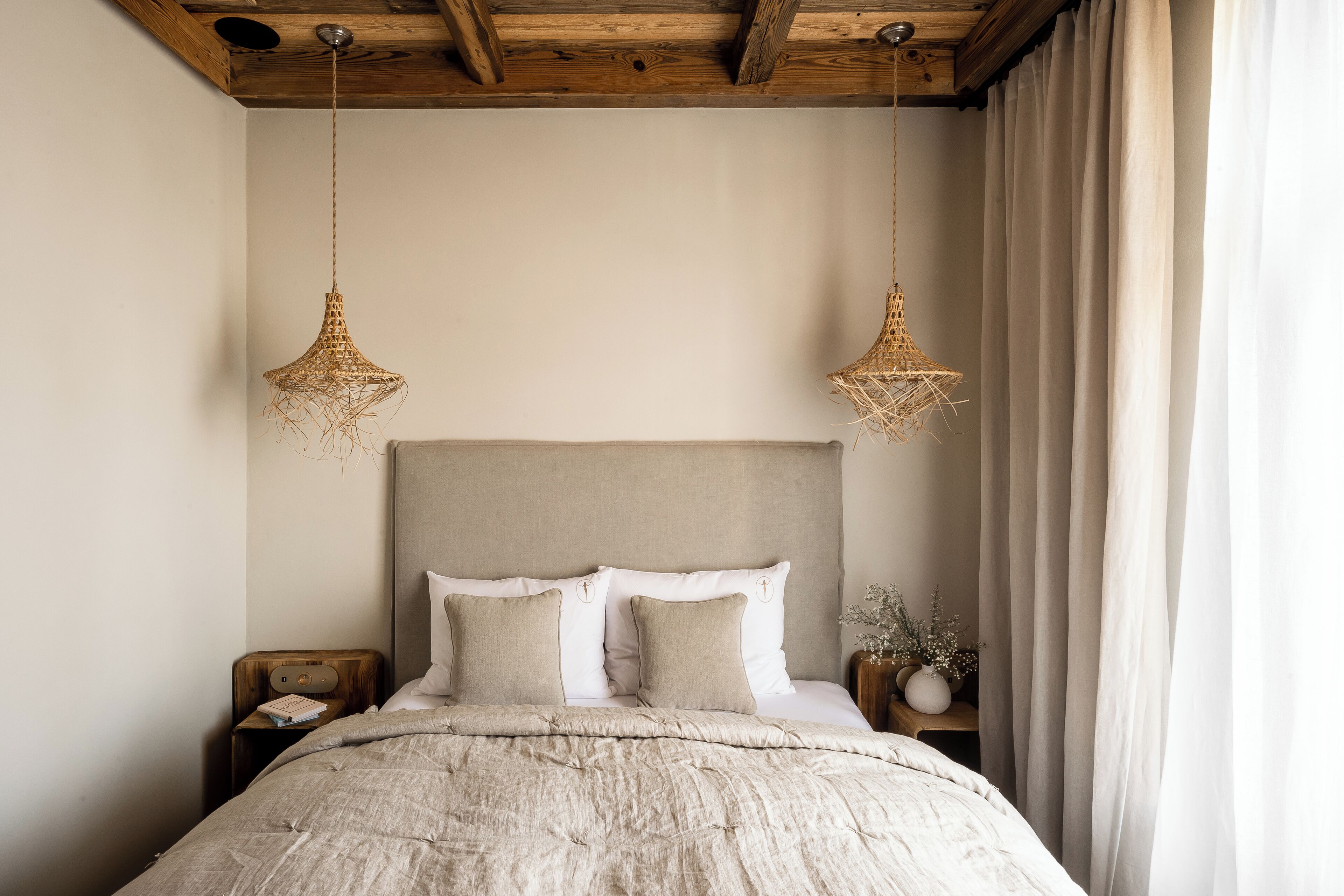 Un dormitorio con una cama grande, dos mesitas de noche e iluminación colgante.
