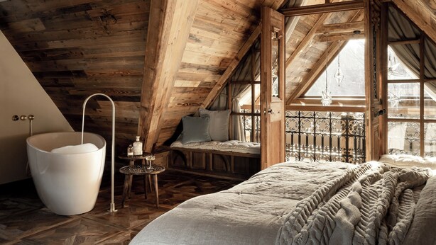 A cozy attic bedroom with a large bathtub, a wooden ceiling, and a window with a view. - VILLA VENA (Zakopane)