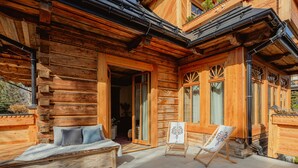 A wooden cabin with a cozy outdoor seating area, a wooden bench, and an easel with a painting. - VILLA VENA (Zakopane)