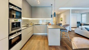 A modern kitchen with built-in appliances, a central island, and a dining area with a sofa and chairs. - Luxury Lakefront Loft in Montreux Swiss Reviera (Territet)